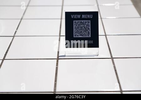 Menü anzeigen und QR-Code-Zeichen auf dem Tisch im Café scannen Stockfoto