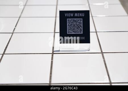 Menü anzeigen und QR-Code-Zeichen auf dem Tisch im Café scannen Stockfoto