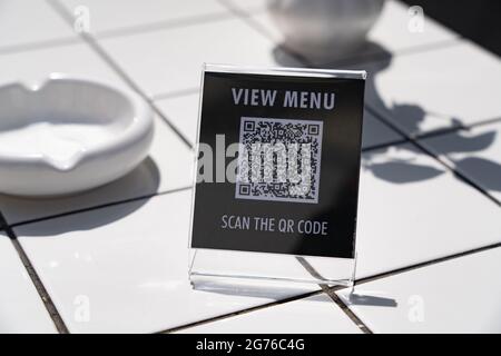 Menü anzeigen und QR-Code-Zeichen auf dem Tisch im Café scannen Stockfoto