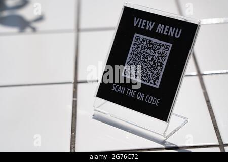 Menü anzeigen und QR-Code-Zeichen auf dem Tisch im Café scannen Stockfoto