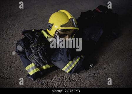 Feuerwehrschutzuniform. Feuerwehrhelm, Schutzhose, Schutzjacke und Handschuhe. Stockfoto