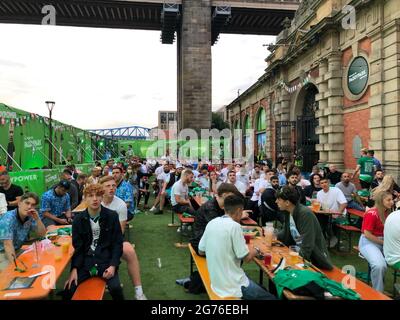 Ein Fan, der auf einen Aussichtspunkt geklettert ist, um vor dem UEFA Euro 2020 Finale zwischen Italien und England die Großleinwand der PaddyPark Fanzone am Fluss Tyne in Newcastle zu sehen. Bilddatum: Sonntag, 11. Juli 2021. Stockfoto