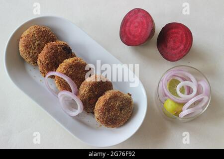 Luftgebratene Rote-Beete-Koteletts. Serviert mit Zwiebeln. Aufgenommen auf weißem Hintergrund Stockfoto