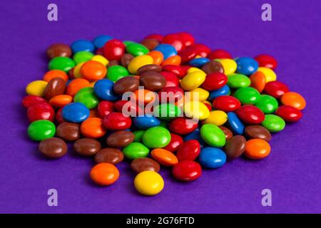 Ein Stapel von Schokolade-Knöpfen mit Regenbogenfarben und Süßigkeiten Stockfoto