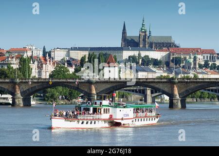 PRAG - Juli 10 das Dampfschiff Vltava fährt am 10. Juli, 2021 in Prag, Tschechische Republik, in See. Kreuzfahrt-Boot Moldau mit Prager Burg im Hintergrund. Stockfoto