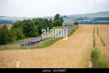 Pewsey, England. 11. Juli 2021. Das Feld passiert Weizenfelder bei den British Cycling Junior National Road Race Championships. Kredit: David Partridge/Alamy Live Nachrichten Stockfoto