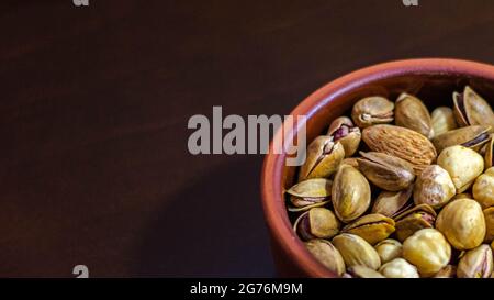 Getrocknete Früchte in einem Topfton, getrocknete Nüsse und Früchte auf einem hölzernen Hintergrund, selektiver Fokus Stockfoto