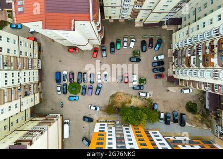 Luftaufnahme von geparkten Autos auf dem Parkplatz zwischen hohen Wohngebäuden. Stockfoto