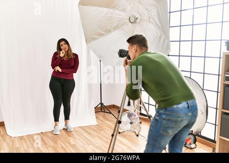 Junge Frau im Fotostudio ernstes Gesicht, das mit der Hand am Kinn über Fragen nachdenkt, über verwirrende Ideen nachdenklich Stockfoto
