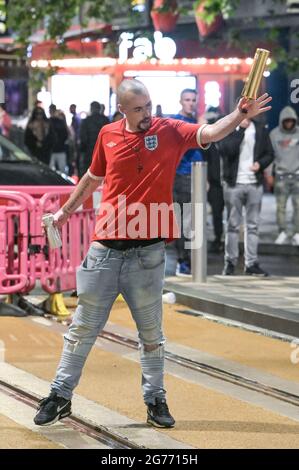 Broad Street, Birmingham 11. Juli 2021 Fans zwickten sich zusammen, nachdem England aus dem EM 2020-Finale mit Italien, das bei den Strafen gewann, abstürzte und es 56 Jahre lang verletzt hatte. Die Fans sprangen aus Pubs und Bars auf die Broad Street im Stadtzentrum von Birmingham, als die Polizei Linien bildete. Viele Fans sahen niedergeschlagen aus, eine Frau sah verloren aus, als sie durch Brunnen ging. Eine Rauchgranate wurde ebenfalls gestartet, als die Polizei versuchte, Unterstützer zu beruhigen, obwohl ein englisches Kit mit Ventilator eine Wodka-Flasche in die Luft winkte, bevor die Polizei drohte, Gas zu verwenden, wenn er es nicht fallen ließ. Der Mann wurde dann eingesperrt. Stockfoto