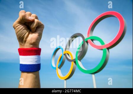 RIO DE JANEIRO - CA. MAI 2016: Sportler mit rot-weißem und blauem Armband schlägt mit der Faust vor den Olympischen Ringen in die Luft Stockfoto