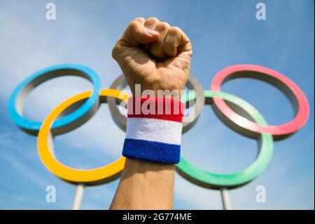 RIO DE JANEIRO - CA. MAI 2016: Sportler mit rot-weißem und blauem Armband schlägt mit der Faust vor den Olympischen Ringen in die Luft Stockfoto