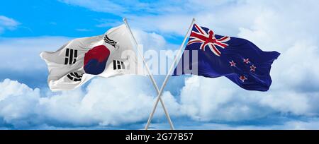Flaggen von Südkorea und Neuseeland winken im Wind auf Fahnenmasten gegen den Himmel mit Wolken am sonnigen Tag. Symbolisieren Beziehung, Dialog zwischen tw Stockfoto