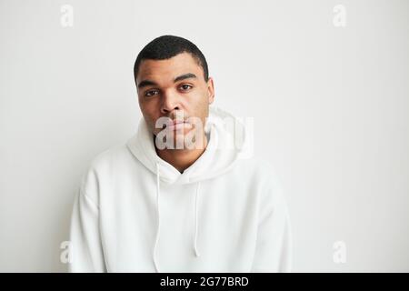 Minimalportrait eines jungen Mannes mit gemischter Rasse, der die Kamera in weißem, kopierfähigem Raum ansieht Stockfoto
