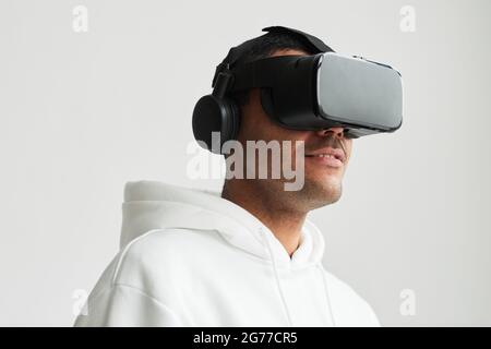 Minimales Porträt eines modernen Mannes mit VR-Headset vor weißem Hintergrund, Kopierfläche Stockfoto