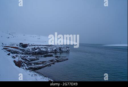 Schnee- und Eisflecken im Dorf Teriberka, Murmansk, Russland. Mär. 2017 Friedhof des Fischerschiffs in der Barentssea. Das polare Klima der Arkti Stockfoto