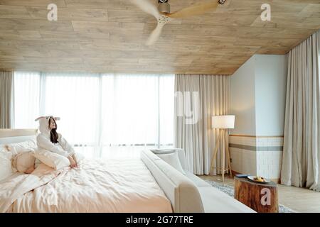 Junge Frau genießt den frühen Morgen nach dem Aufwachen in einem großen, bequemen Bett Stockfoto