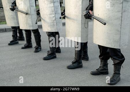 Eine Gruppe von Polizeikräften, die sich mit Schlagstöcken durch die Straße bewegt, während sie koordinierte Aktionen gegen Demonstranten durchführt Stockfoto