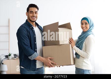 Hübsche Frau im Hijab, die ihrem Mann Papierkartons gab Stockfoto