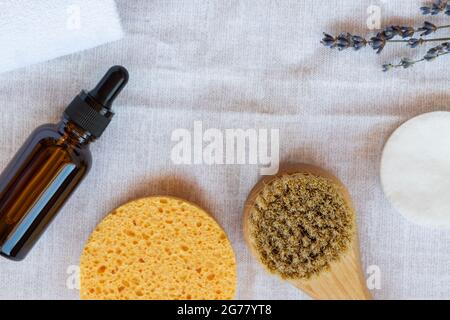 Flache Lay-Komposition mit Lavendelblüten, Badezimmerzubehör und Naturkosmetik auf weißem Baumwolltuch-Hintergrund. Stockfoto