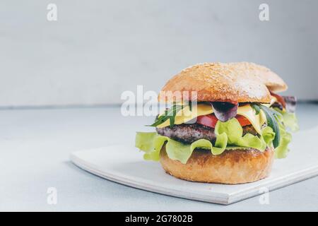 Hamburger mit Rindfleisch, Tomaten, Käse, Salat, Spinat, Rucola und Zwiebeln Stockfoto
