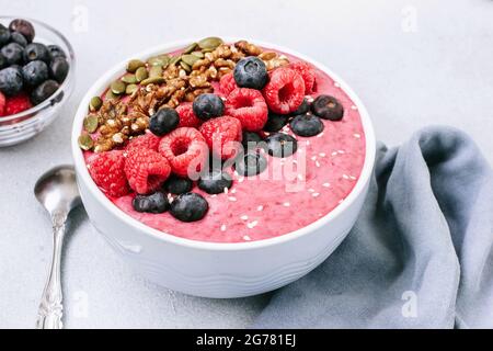 Acai Schale mit Smoothies mit Himbeeren, Heidelbeeren, Walnüssen, Kürbiskernen und Sesam Stockfoto