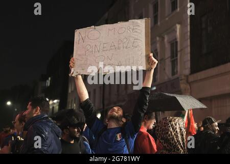 London, Großbritannien. Juli 2021. Italien-Fan hält ein Plakat, auf dem nach ihrem Sieg bei der UEFA Euro 2021 keine Ananas auf Pizza verlangt wird. Massen von Fußballfans blieben im Zentrum Londons, nachdem Italien den Meister der UEFA Euro 2021 in den Strafstrafen gewonnen hatte. Italien-Fans feierten ihren Sieg und ließen die England-Fans im Regen schluchzen. (Foto von Hesther Ng/SOPA Images/Sipa USA) Quelle: SIPA USA/Alamy Live News Stockfoto