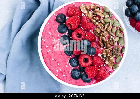 Acai Schale mit Smoothies mit Himbeeren, Heidelbeeren, Walnüssen, Kürbiskernen und Sesam Stockfoto