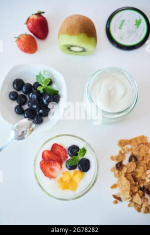 Tisch mit Joghurt, Müsli und Beeren zum Frühstück Stockfoto
