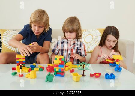 Kinder spielen mit bunten Spielzeugsteinen zusammen am Tisch im hellen Spielzimmer Stockfoto