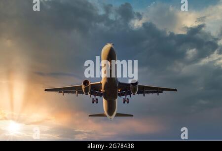 Flugzeug landet bei Sonnenuntergang am Flughafen mit Wolken im Hintergrund Stockfoto