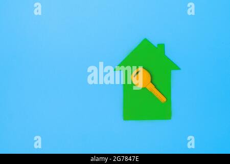 Gelber Schlüssel auf einem Miniaturmodell Haus. Eco House-Konzept. Flach, oben liegend, Kopieplatz. Minimalistischer Style. Trendiges Öko-Haus in der Natur Stockfoto