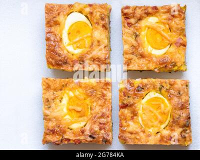 Vier Stücke salziger Kuchen mit halben Eiern auf einem transparenten Teller. Bild von oben. Stockfoto