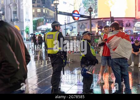 Polizeibeamte sprachen beim Zirkus Piccadilly während des Euro 2020-Finales zwischen England und Italien mit Fußballfans Stockfoto