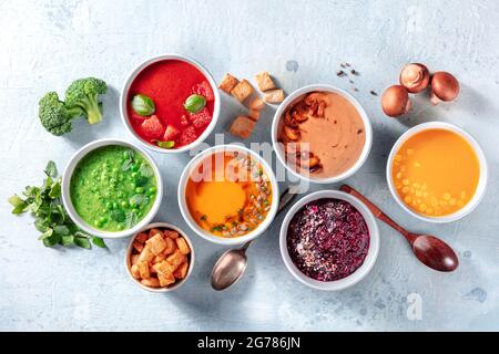 Vegane Suppenvielfalt, von oben geschossen. Grüne Erbse, kalte Tomaten, Kürbis, Pilzbete und süße Maissuppen mit Zutaten Stockfoto