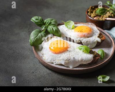 Croque-madame mit Spiegelei, Pesto-Sauce und Basilikum. Traditionelles Französisches Geröstetes Sandwich. Französische Küche. Kopierbereich, selektiver Fokus Stockfoto