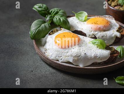 Croque-madame mit Spiegelei, Pesto-Sauce und Basilikum. Traditionelles Französisches Geröstetes Sandwich. Französische Küche. Kopierbereich, selektiver Fokus Stockfoto