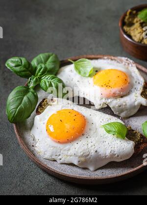 Croque-madame mit Spiegelei, Pesto-Sauce und Basilikum. Traditionelles Französisches Geröstetes Sandwich. Französische Küche. Kopierbereich, selektiver Fokus Stockfoto