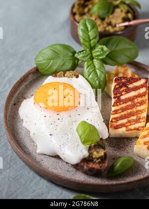 Croque-madame mit Spiegelei, Pesto-Sauce und Basilikum auf einem Leinentischtuch. Traditionelles Französisches Geröstetes Sandwich. Französische Küche. Speicherplatz kopieren, selektiv Stockfoto