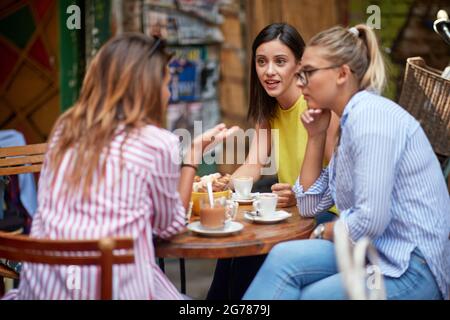 Gruppe von jungen erwachsenen kaukasischen weiblichen Freunden reden, sitzen im Café im Freien, Kaffee trinken. Serious talk, Gespräch Stockfoto