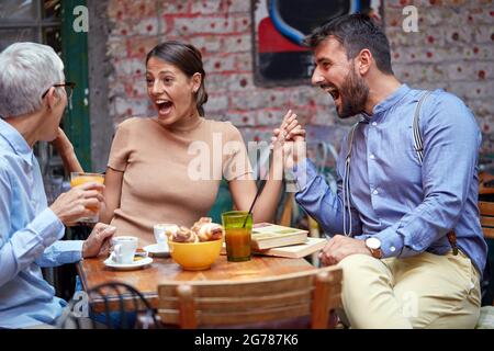 Unterschiedliche Alters- und Geschlechtszugehörigkeit der Menschen, die mit offenem Mund überrascht aussehen, lachen und die Hände halten Stockfoto