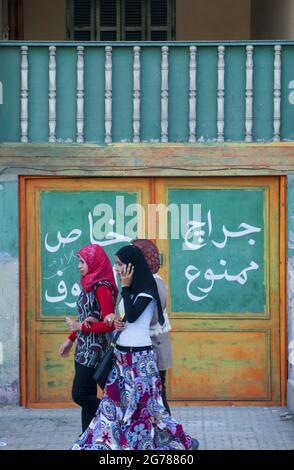 Straßenszene, als eine Gruppe junger Frauen in Alexandria, Ägypten, an einer Tür vorbeikommt Stockfoto