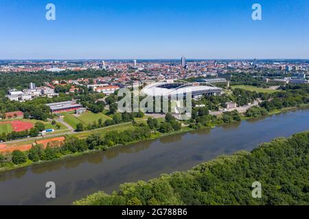 14. Juni 2021, Sachsen, Leipzig: Die Red Bull Arena liegt am Rande der Innenstadt, direkt am Elster-Hochwasserbett. Das Heimgelände von RB Leipzig wird umgebaut. Die Zuschauerkapazität erhöht sich von 42,558 auf 47,069 im Stehen und Sitzen. Die Außenseite des Stadions ist von einer schalldichten Fassade umgeben. Der Damm des ehemaligen Zentralstadions, das die Arena umfasst, wurde hinter dem historischen Glockenturm aufgeschnitten, um Platz für einen neuen Eingang zu schaffen. RB Leipzig investiert bis 2022 gut 60 Millionen Euro in den Umbau. (Luftaufnahme mit Drohne) Foto: Jan Woitas/dpa-Zentralbild Stockfoto