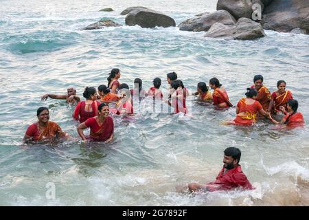 Gruppe von hindu-Gläubigen in roten Kleidern, die im Ozean baden, Kanyakumari, Laccadive Sea, Tamil Nadu, Indien Stockfoto