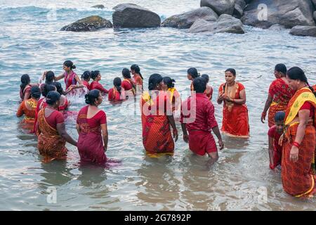 Gruppe von hindu-Gläubigen in roten Kleidern, die im Ozean baden, Kanyakumari, Laccadive Sea, Tamil Nadu, Indien Stockfoto