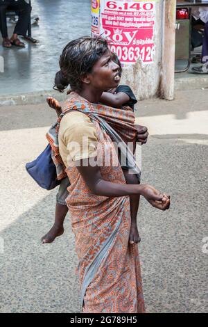 Junge indische Frau, die Kind trägt, bittet um Geld von Fahrgästen im Bus, Tamil Nadu, Indien Stockfoto