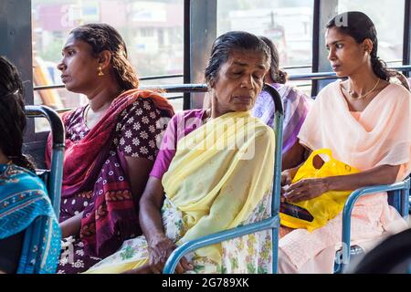 Vier indische Fahrgäste mit bunten Saris im öffentlichen Bus, Kovalam, Kerala, Indien Stockfoto