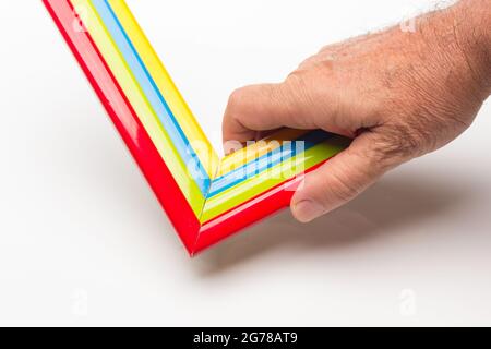 Hand, Finger und verschiedene Farben; Buntstifte, voller Bereich; farbige Winkel, die von der Hand eines Erwachsenen gehalten werden Stockfoto