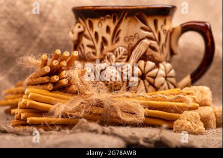 Brotstangen mit Salz, gebunden mit einer Schnur und einem Becher aus Steingut für Tee. Nahaufnahme Selektiver Fokus Stockfoto