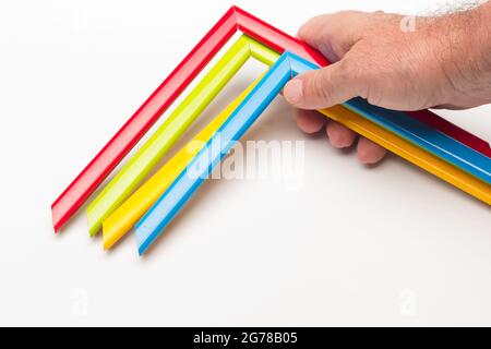 Hand, Finger und verschiedene Farben; Buntstifte, voller Bereich; farbige Winkel, die von der Hand eines Erwachsenen gehalten werden Stockfoto